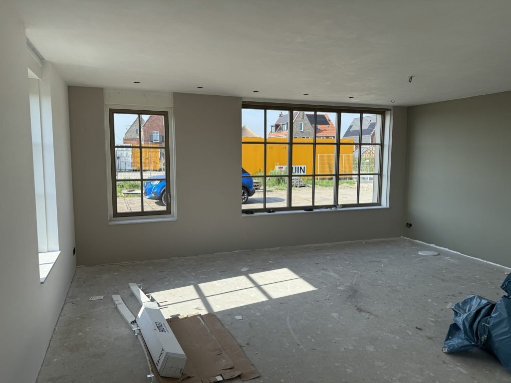 Nieuwbouwkamer met wanden in een warme grijstint en grote raampartijen